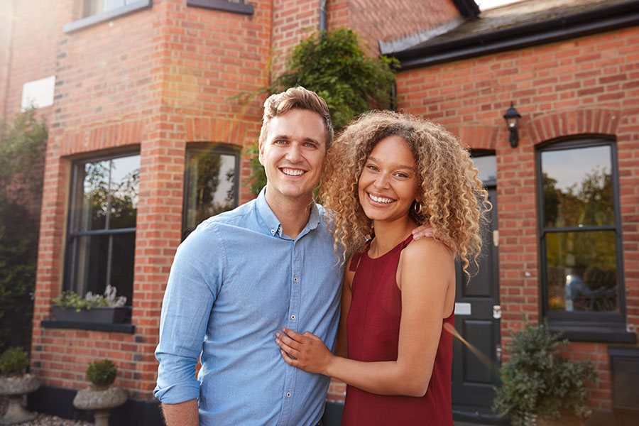 Personal Insurance - Portrait of Excited Young Couple Standing outside of Their New Home Together